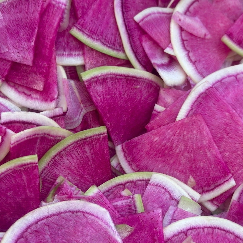 Close-up of sliced pink watermelon radishes with green edges.