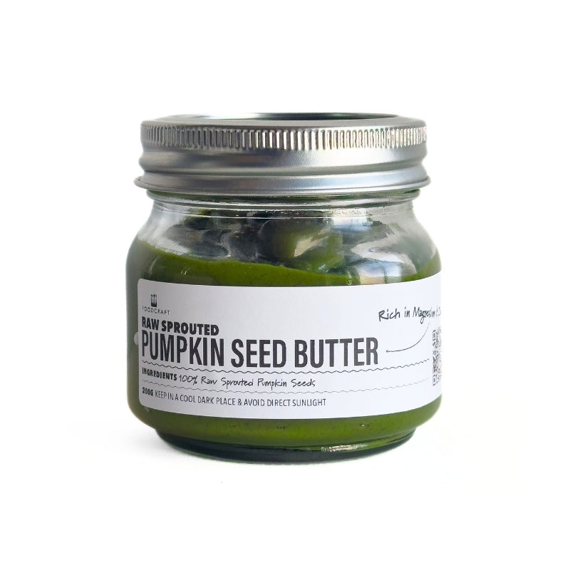 Jar of raw sprouted pumpkin seed butter with a metal lid on a white background